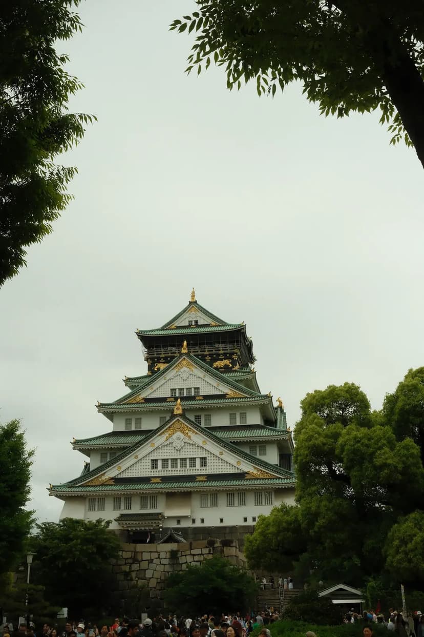 Osaka Castle framed by green trees under a clear sky
